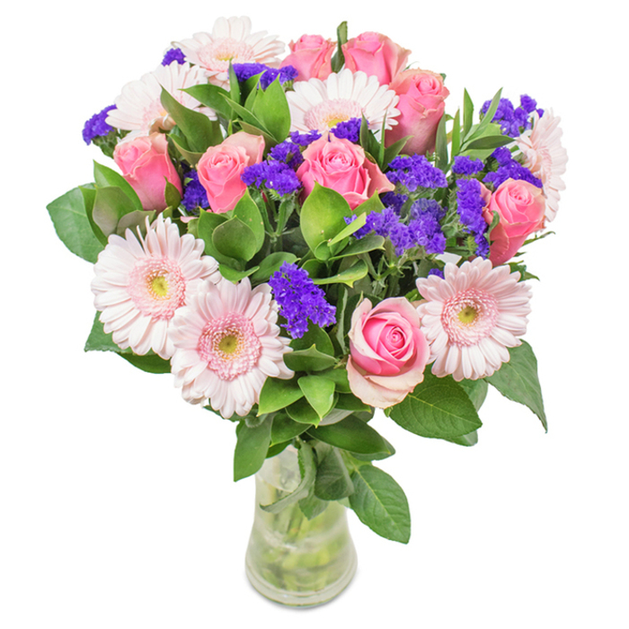 Set against a pristine backdrop in Southfields, this vibrant and elegantly arranged bouquet showcases a harmonious blend of about seven to nine soft to mid-pink roses, each bloom at a different stage, from tightly furled buds to open spirals brimming with classic charm. Five to seven pale pink gerbera daisies, easily recognized by their generous, round petals and nearly white centers, nestle alongside the roses, creating a gentle, balanced focal point. Interspersed among these main blooms are lively clusters of purple statice, their vivid colours and textured forms offering a bold yet refined contrast. Encompassing the arrangement, deep green foliage delivers a rich, natural base, enhancing freshness and underscoring a connection to Southfields' beloved green spaces. The transparent vase highlights the bouquet's structural beauty, visible stems, and sparkling water, evoking the sensation of a just-picked garden gift. This arrangement, ideal for birthdays, anniversaries, Mother's Day, or bringing joy to an office near Augustus Road, is a tangible expression of affection, celebration, and local Southfields elegance, thoughtfully created with the community in mind.